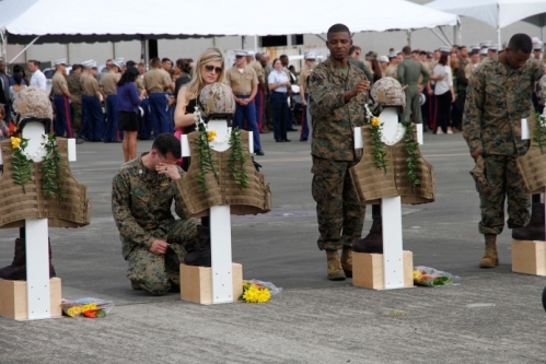 Mourners pause at crosses representing the 12 Marines who died in helicopter crashes Jan. 14 in Hawai. The crosses were adorned with flight gear, boots and Hawiian leis during a memorial Friday at Marine Corps Base Hawaii. WYATT OLSON/STARS AND STRIPES